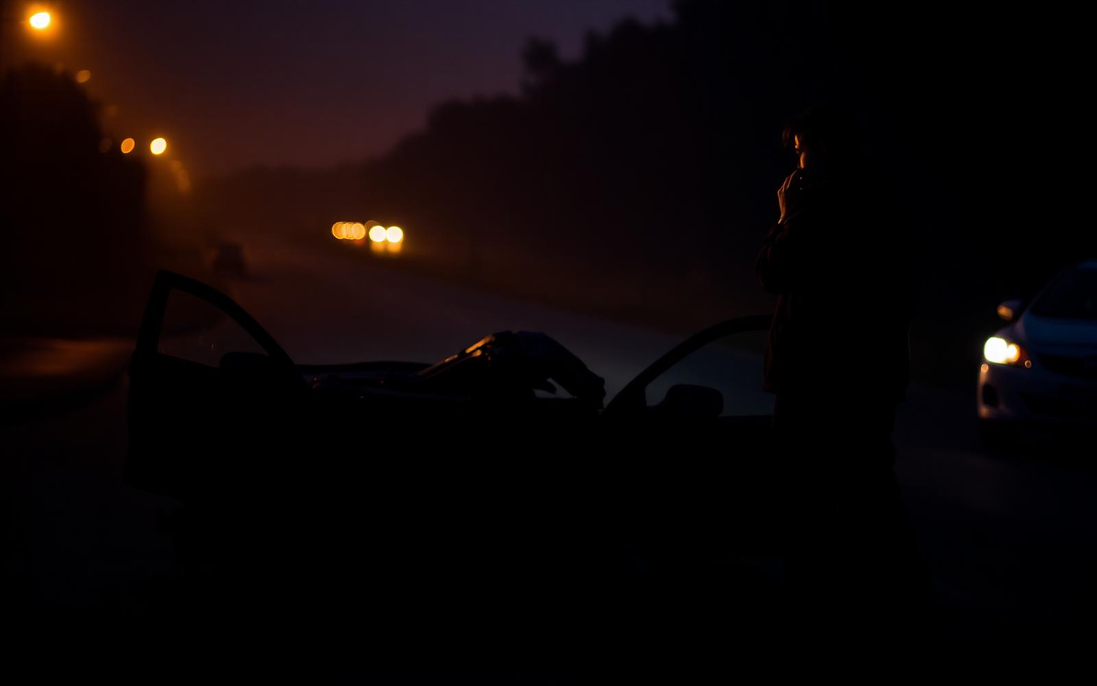 Person on phone next to damaged car after accident